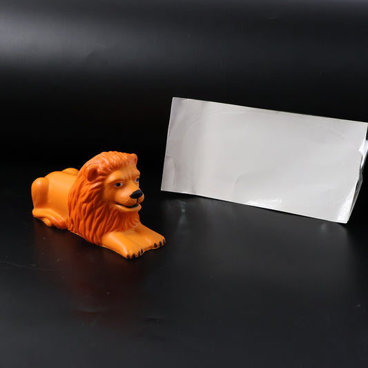 Golden orange lion figurine in a lying pose on a car dashboard, view 2