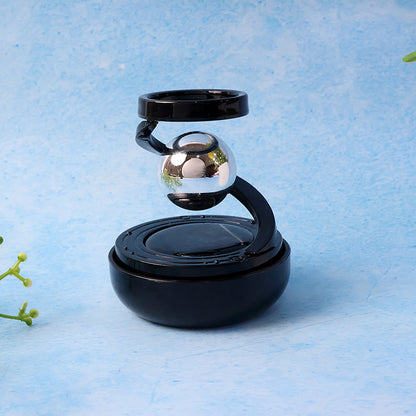 Solar rotating car air freshener with metallic spinning orb on dashboard, view 3