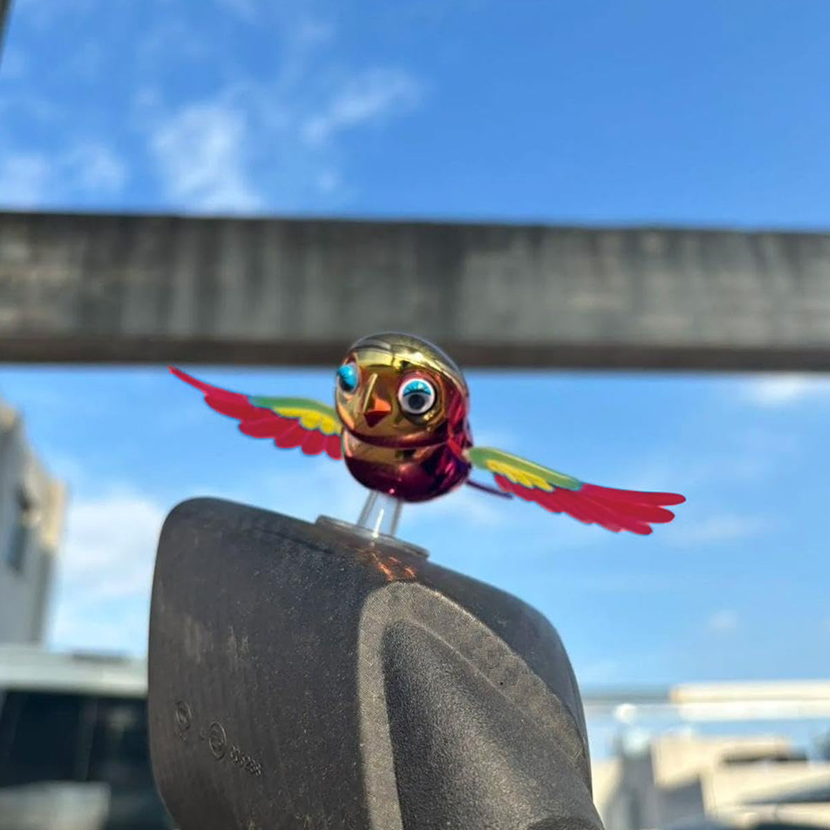 Colourful wind flying bird decoration on a car dashboard, view 5